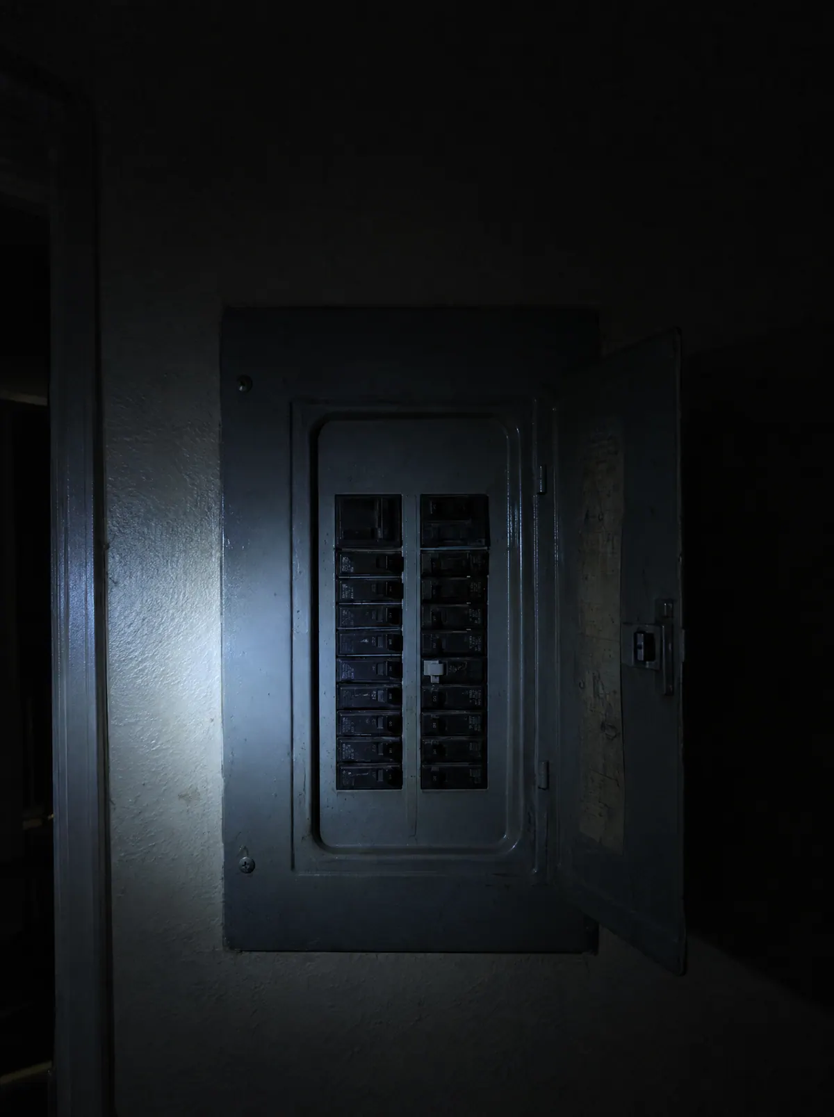 A breaker panel lit by a phone flashlight during a power outage